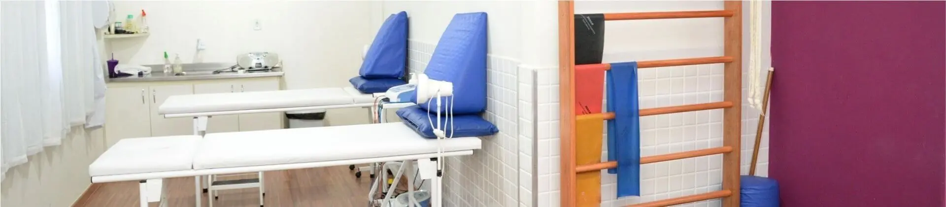 Sala de atendimento com macas, espaldar e faixas elásticas